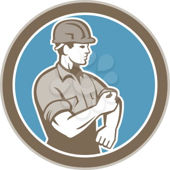 Illustration of a construction worker wearing hardhat rolling up sleeve facing side set inside circle on isolated background done in retro style.