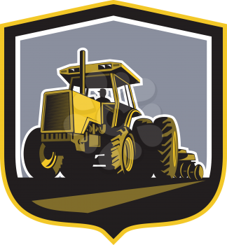 Illustration of a farmer driving riding vintage tractor plowing field front view set inside a shield crest done in retro style.