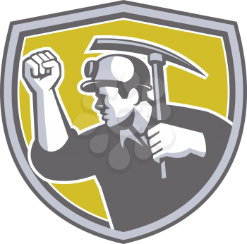 Illustration of a coal miner wearing hardhat wiith clenched fist holding pick axe viewed from the side set inside shield crest on isolated background done in retro style. 