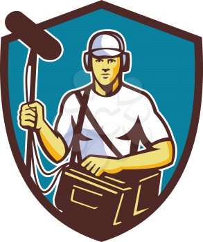 Illustration of a soundman film crew worker with headphone carrying bag holding a telescopic microphone facing front set inside shield crest on isolated background done in retro style.