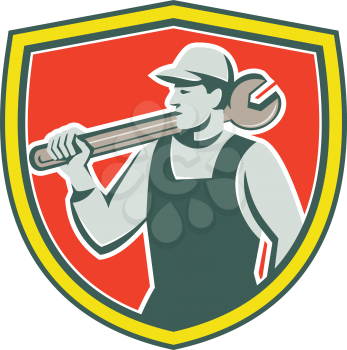 Illustration of a mechanic holding spanner on shoulder looking to the side set inside shield crest on isolated background done in retro style. 
