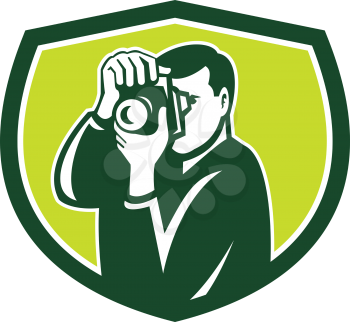 Illustration of a photographer shooting with dslr digital camera set inside shield crest done in retro style.