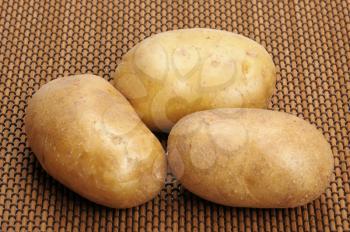 Royalty Free Photo of Three Potatoes on a Brown Mat