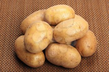 Several brown potatoes lies on a mat