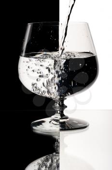 Glass with a water, on a black and white background.