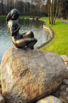 Bronze sculpture of a girl on a rock in a city park