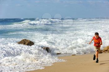 Boy runs along the shore of the Mediterranean Sea in Israel