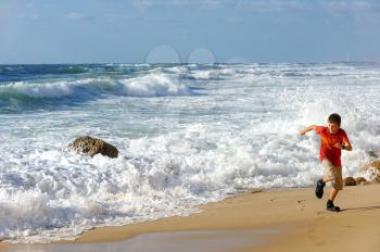 Boy runs along the shore of the Mediterranean Sea in Israel