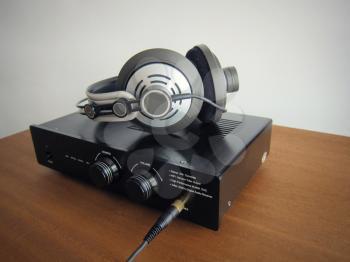 Black DAC Headphone amplifier with connected headphones on the wooden desk
