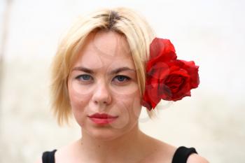 A stunningly beautiful young blond woman with red flower in hair