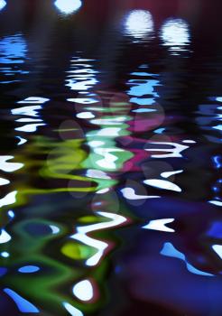 reflection in water of colorful holiday lights