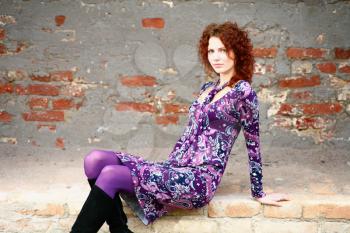 closeup headshot portrait of an attractive young redhead woman beside a brick wall