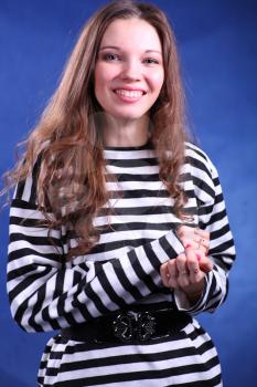 Young brunette lady in stripped dress posing on grey background