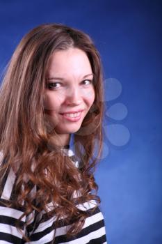 Young brunette lady in stripped dress posing on grey background