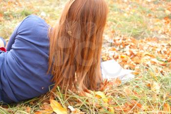 Young Woman  Leaning Book outdoors in autumn park