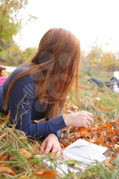 Young Woman  Leaning Book outdoors in autumn park