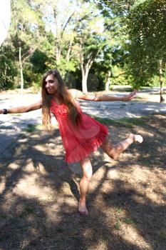 Portrait of a sexy young female in a park in red dress