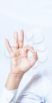 Businessman's hand showing OK sign, studio shot on gray background.  High resolution