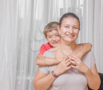 Happy mother with the son on light background indoors living room