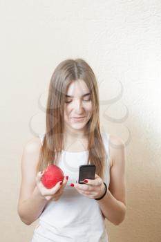 Beautiful blonde woman holding a red apple and cell phone - health concept. Pretty smile deep blue eyes