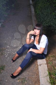 beautiful young woman outdoors sitting, alley in the dark