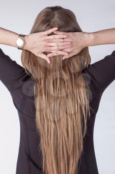 Beautiful nude young woman with very long blond hair rear view on white background