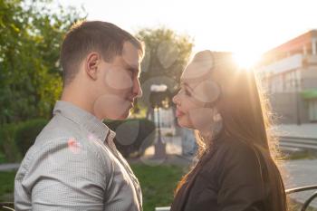 Cute Caucasian couple pose for the camera outdoors with town on background