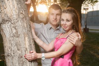 Young couple in love. Portrait of a passionate couple in love embracing near tree sunset backlit