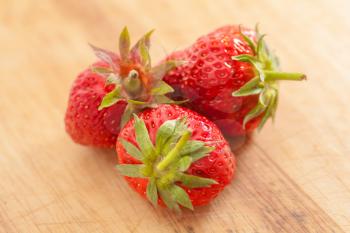 strawberries on wooden table - Three strawberries, Fragaria