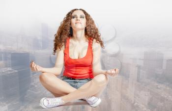 young woman do yoga meditation against blurred cityscape her eyes closed