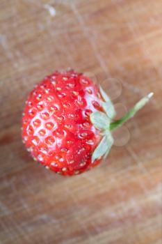 one strawberry on the wooden plank, macro or very closeup shot