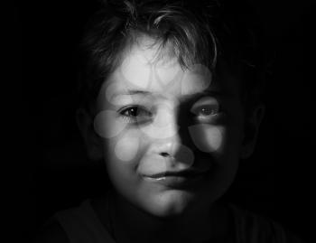 black and white shot of the boy in the dark, focused light on the head