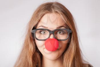 Close-up portrait of a happy 20s girl with red clown nose