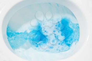 Blue water flow. Toilet bowl closeup with blue water