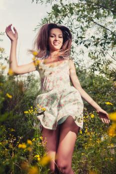 Happy girl dancing outdoors in summer grass