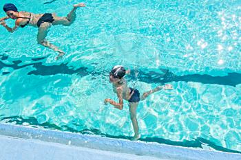 Mother giving son a swimming lesson in pool during summer a lot of copyspace