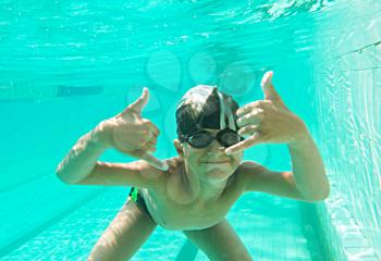 Portrait of a cute little boy swimming underwater and gesturing - OK sign and a lot of copyspace