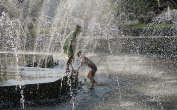 Two Children Through City Park Fountain Water Playing in water together (unrecognizable people)