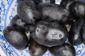 Set of Big black olives in the bowl. Top view macro image.