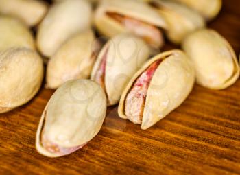 Salted pistachio nuts lying a lot on wooden background macro image