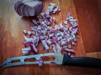 Cutted in pieces shallot onion with steel knife on foreground.