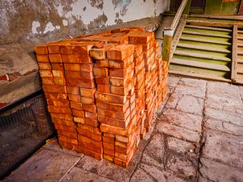 Stack of red bricks for construction purpose in the old house backyard.
