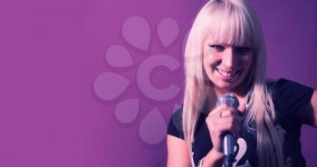 Beautiful singing lady blond hair. Beautyful woman singer sing with microphone karaoke song on stage with violet and pink color gradient.