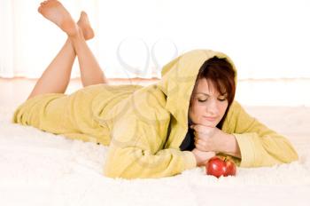 Woman in robe with  apple lying on the floor