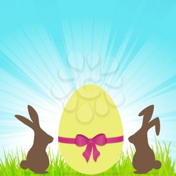 Yellow Easter Egg with Ribbon and Bow and Bunnies Brown Silhouette on Green Grass Over Blue Sunny Sky