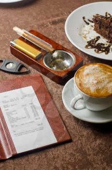 check, ashtray, cigar, lighter and coffee at restaurant table