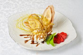 Dessert of pancake with banana, ice-cream, caramel, strawberry and mint