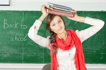Young student girl with her books at blackboard background