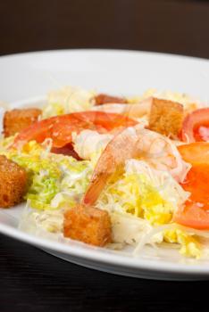 Salad of tiger shrimps, lettuce, chinese cabbage, tomato, garlic rusk, parmesan cheese and sauce