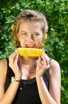 Close-up outdoor portrait of young beauty woman eating corn-cob